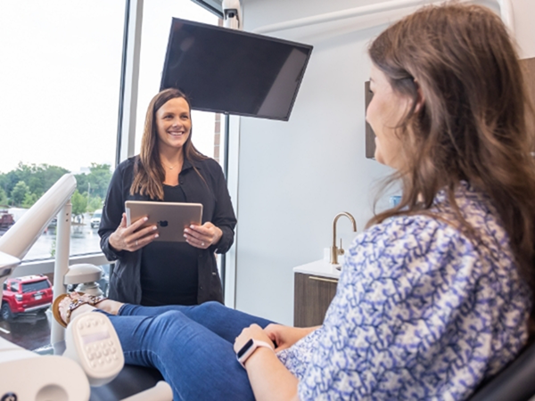 Dental team member holding a tablet and smiling at a patient