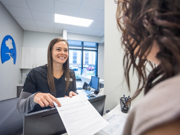 Dental team member handing paperwork to a patient