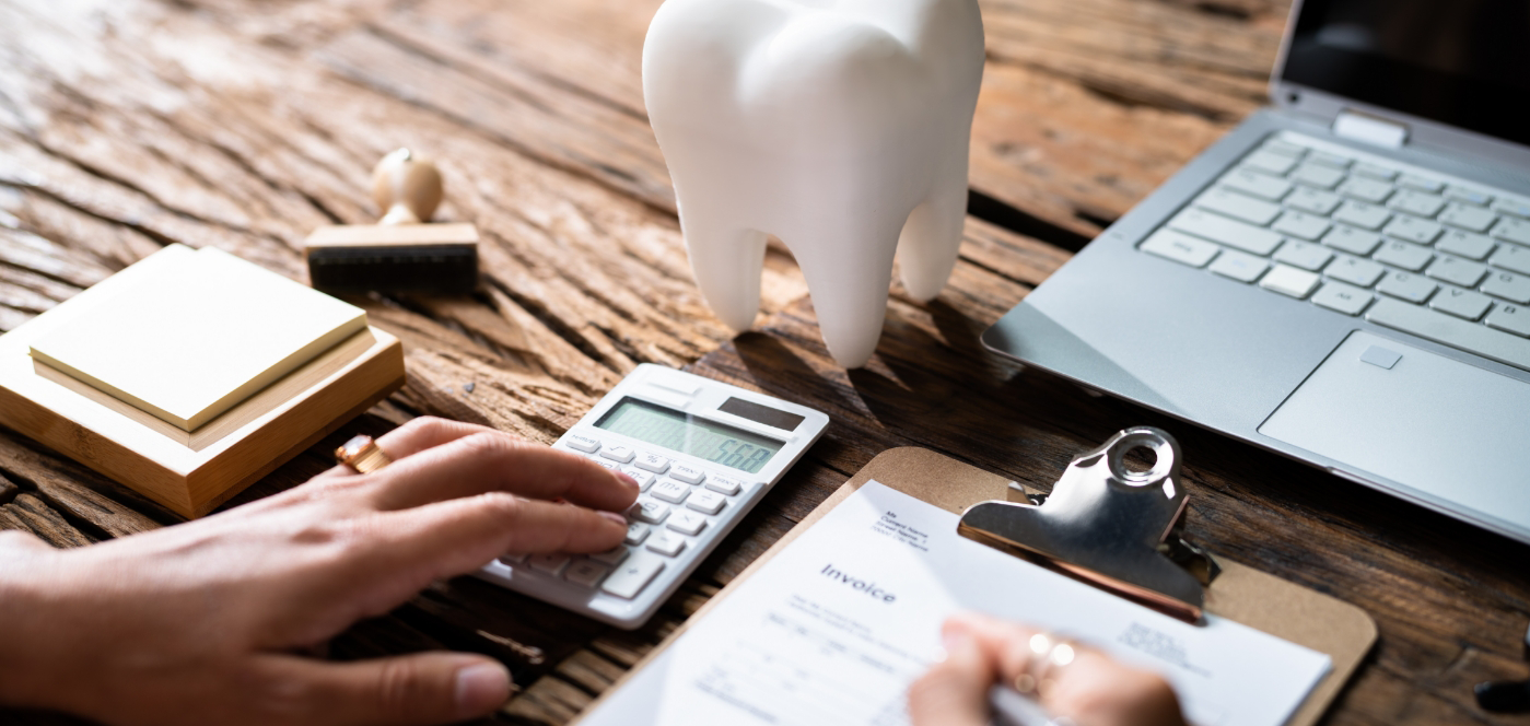 Person typing on calculator while filling out dental insurance paperwork