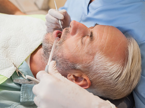 Man with gray hair receiving a dental exam