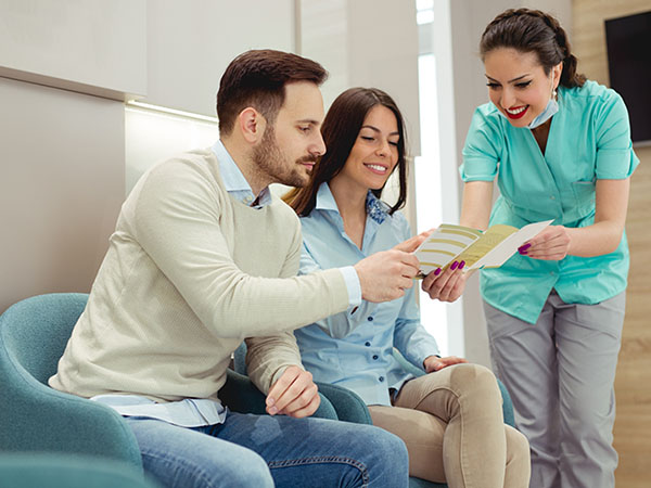 Dental team member showing a pamphlet to two patients