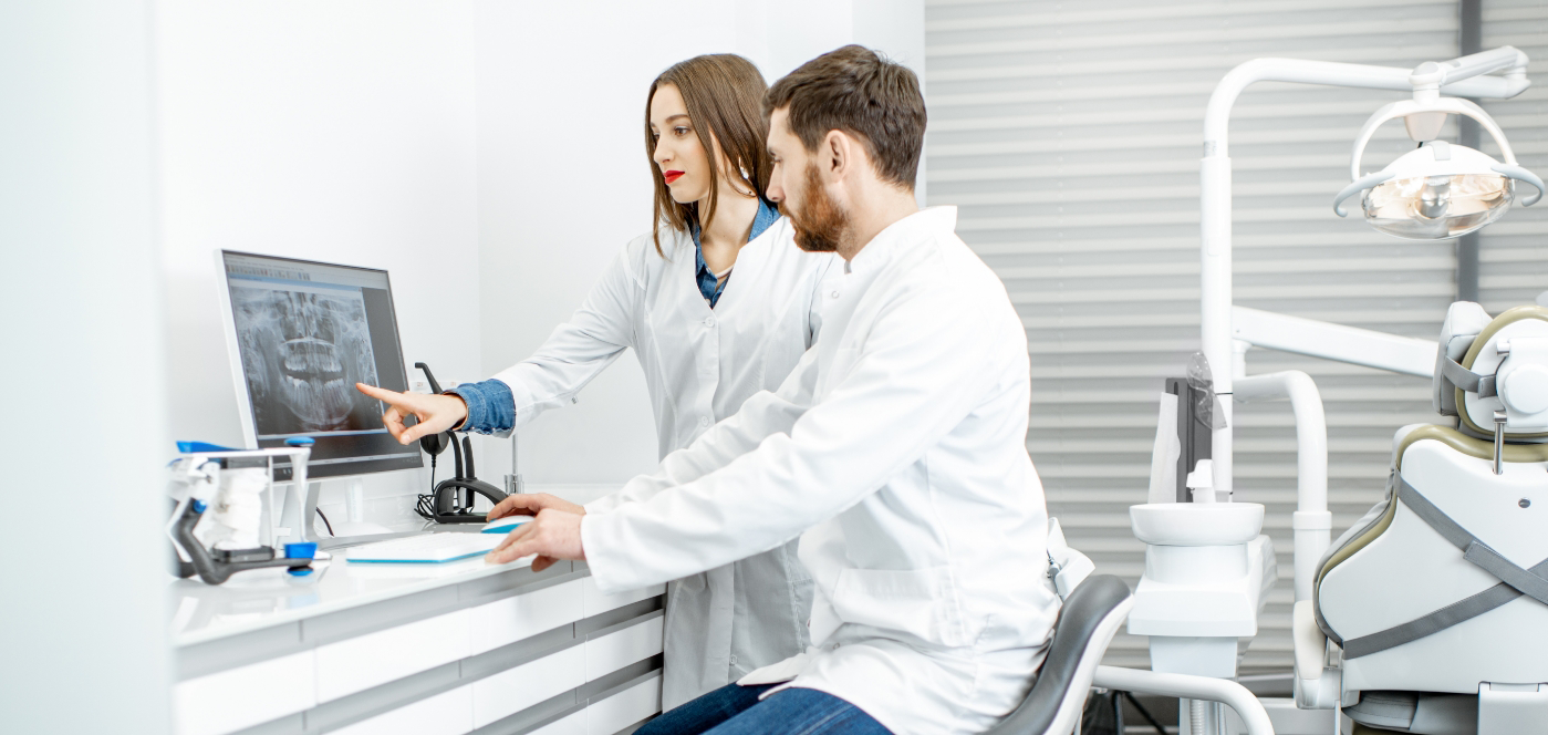 Two dentists looking at an x ray of teeth on a computer