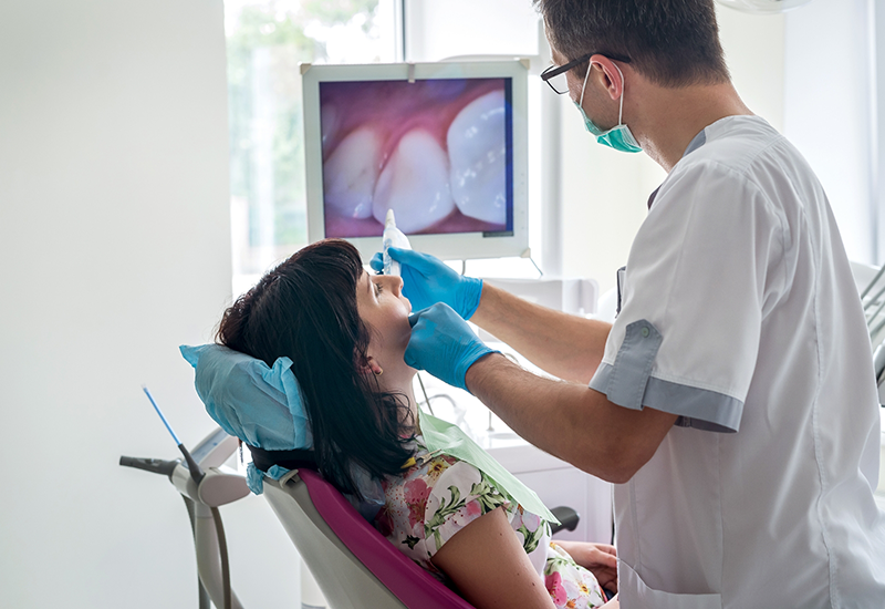 Dentist taking photos of a patients teeth and showing them on a screen