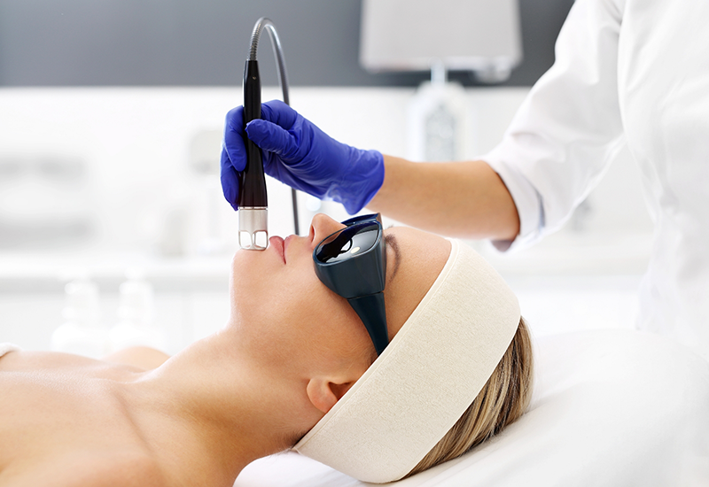 Dentist applying a pen like laser device to a patients chin