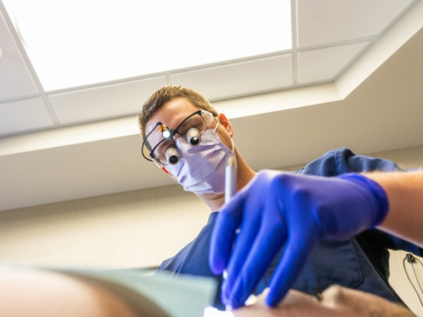 Dentist wearing dental binoculars while treating a patient