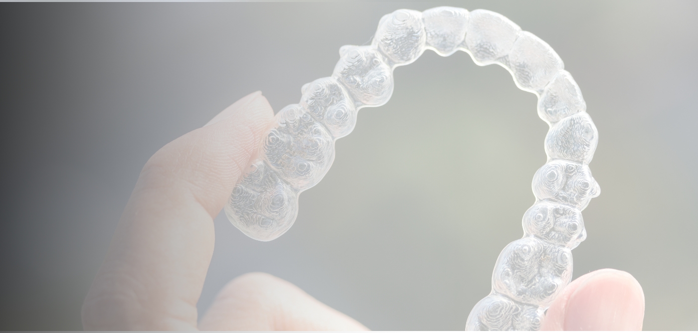 Hand holding an Invisalign aligner