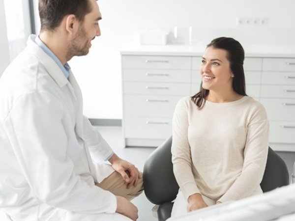 Woman in dental chair smiling while listening to her dentist