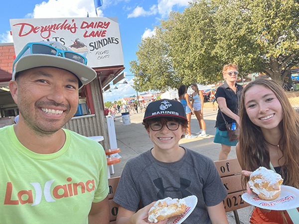 Doctor Brunner with his two children holding funnel cakes at an outdoor festival