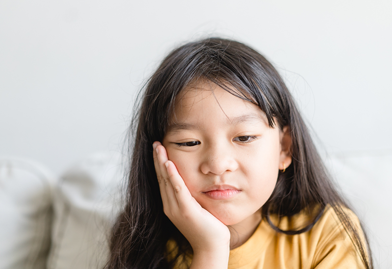 Young girl resting her chin on her hand and looking dissatisfied