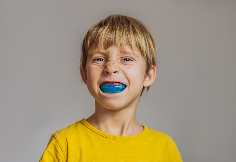 Young boy wearing a blue oral appliance over his teeth