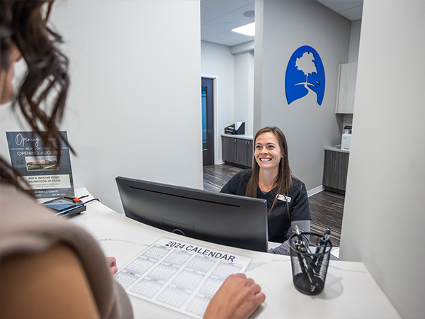 Dental office receptionist smiling at a patient at front desk