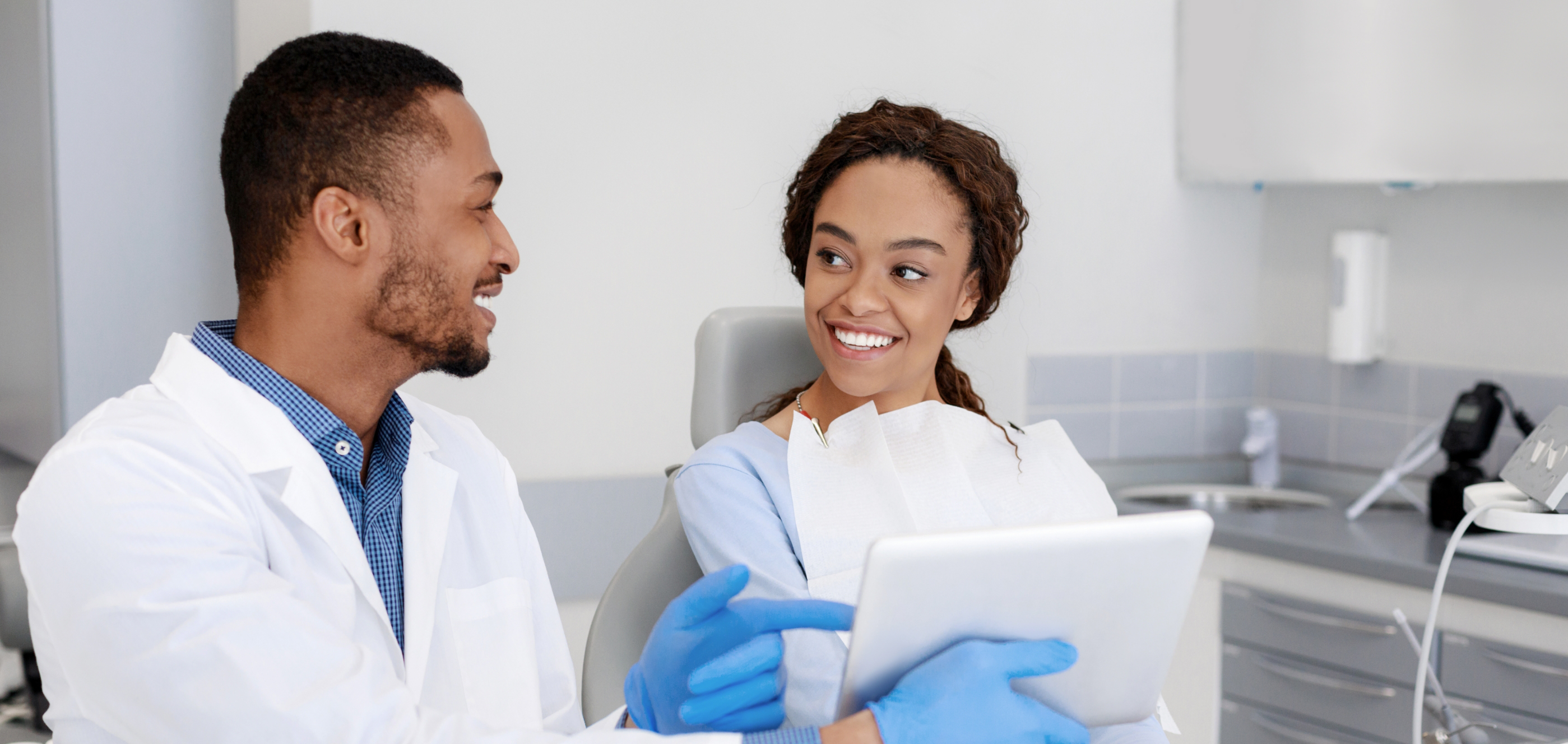 Dental patient smiling as her dentist shows her a tablet