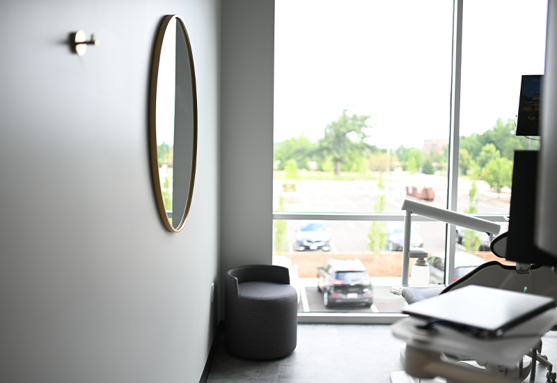 Dental treatment room with mirror on wall and view of parking lot from window