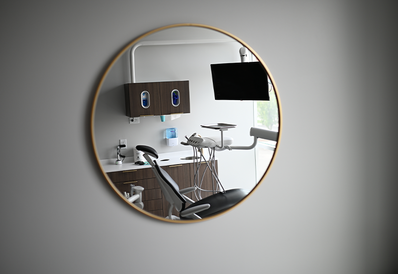 Mirror on wall reflecting dental treatment chair