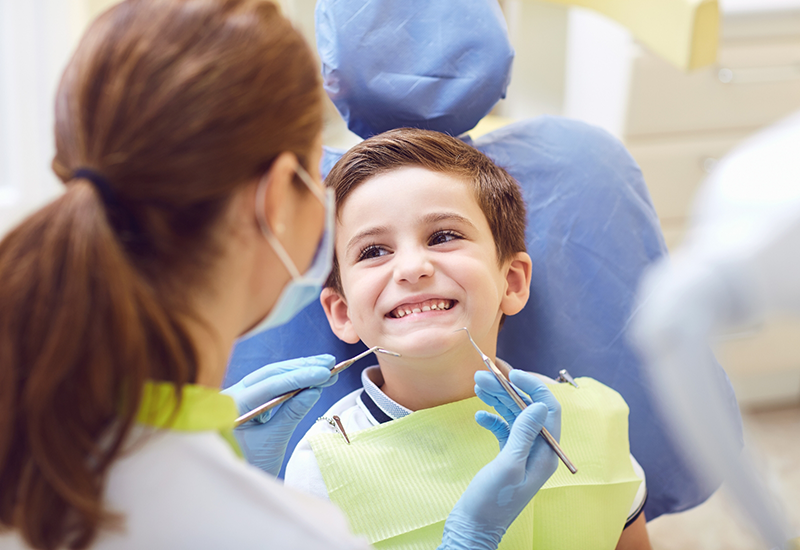 Young boy in dental chair grinning at his dentist