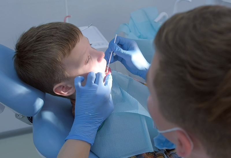 Young boy in dental chair having fluoride applied onto his teeth