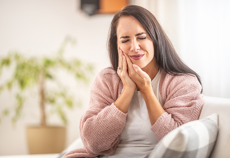 Woman wincing in pain and holding the side of her face