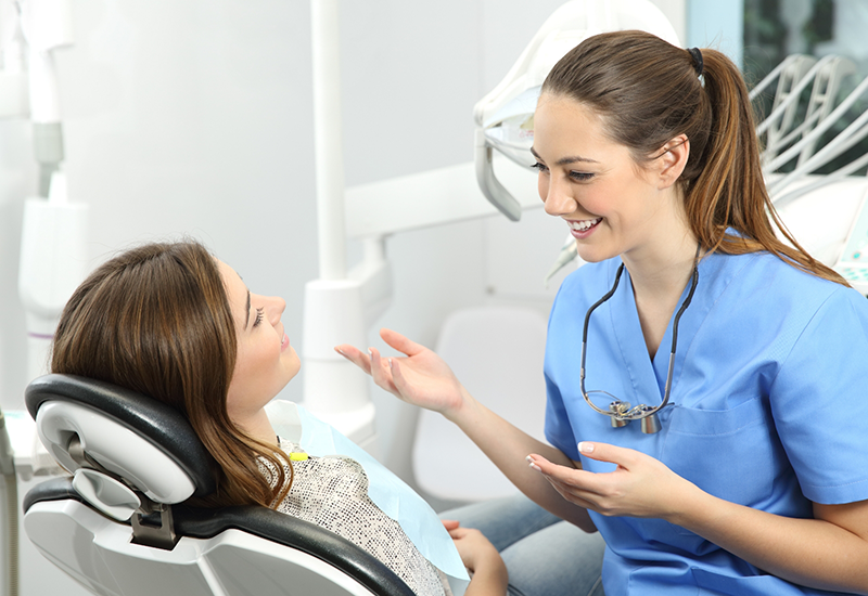 Dentist smiling while talking to a patient in the dental chair