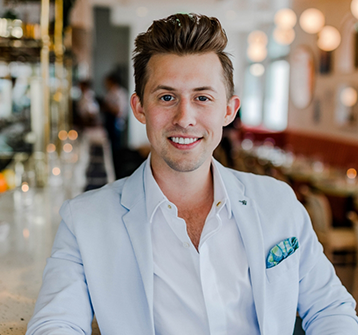 Man in white suit jacket smiling in restaurant