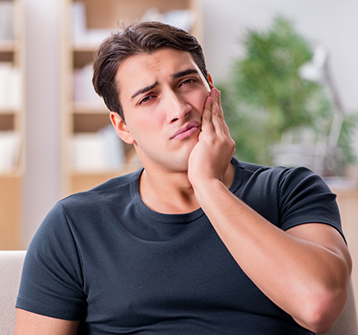 Man wincing and holding the side of his face in pain