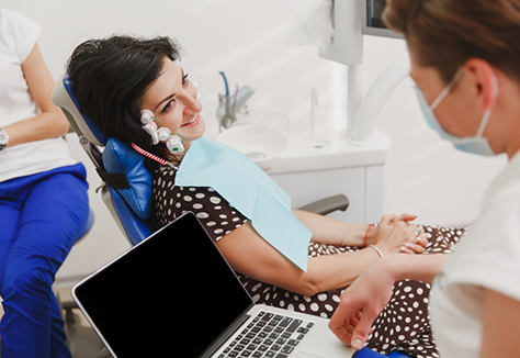 Woman in dental chair wearing several patches on the sides of her face