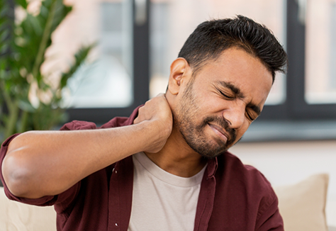 Man holding the back of his neck and wincing in pain