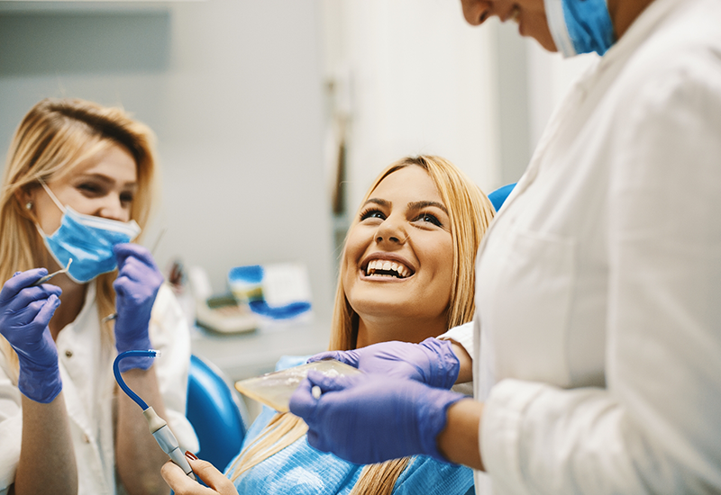 Woman in dental chair grinning at her dentist