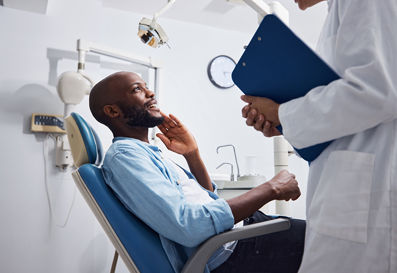 Man touching the side of his jaw while talking to his dentist